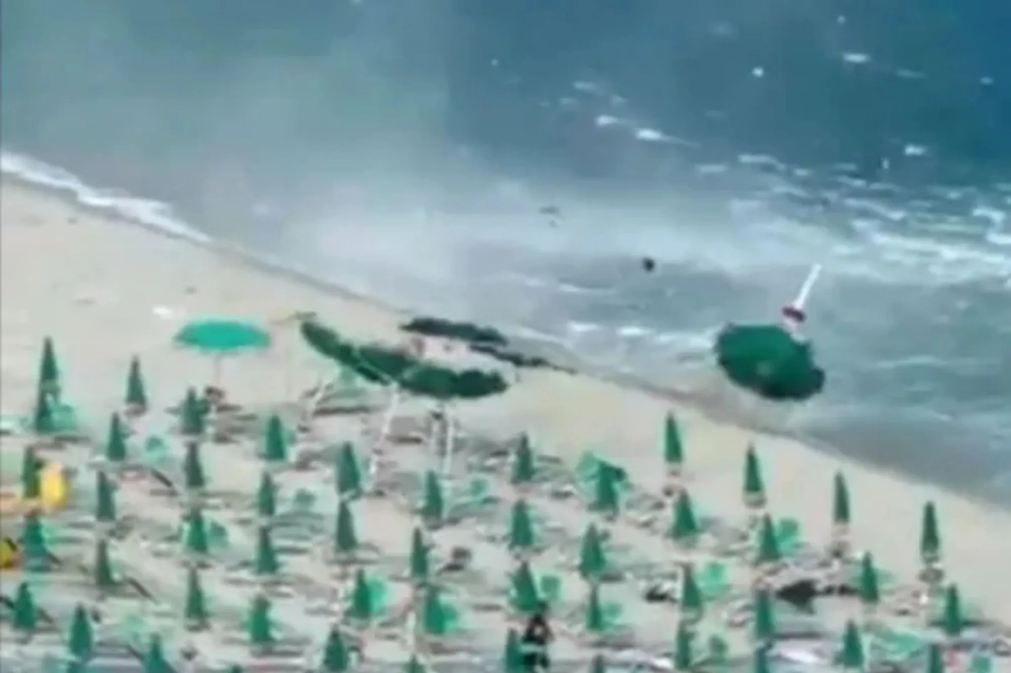 Moment towering waterspout tornado slams into beach in Italy sending parasols flying into air as panicked tourists flee