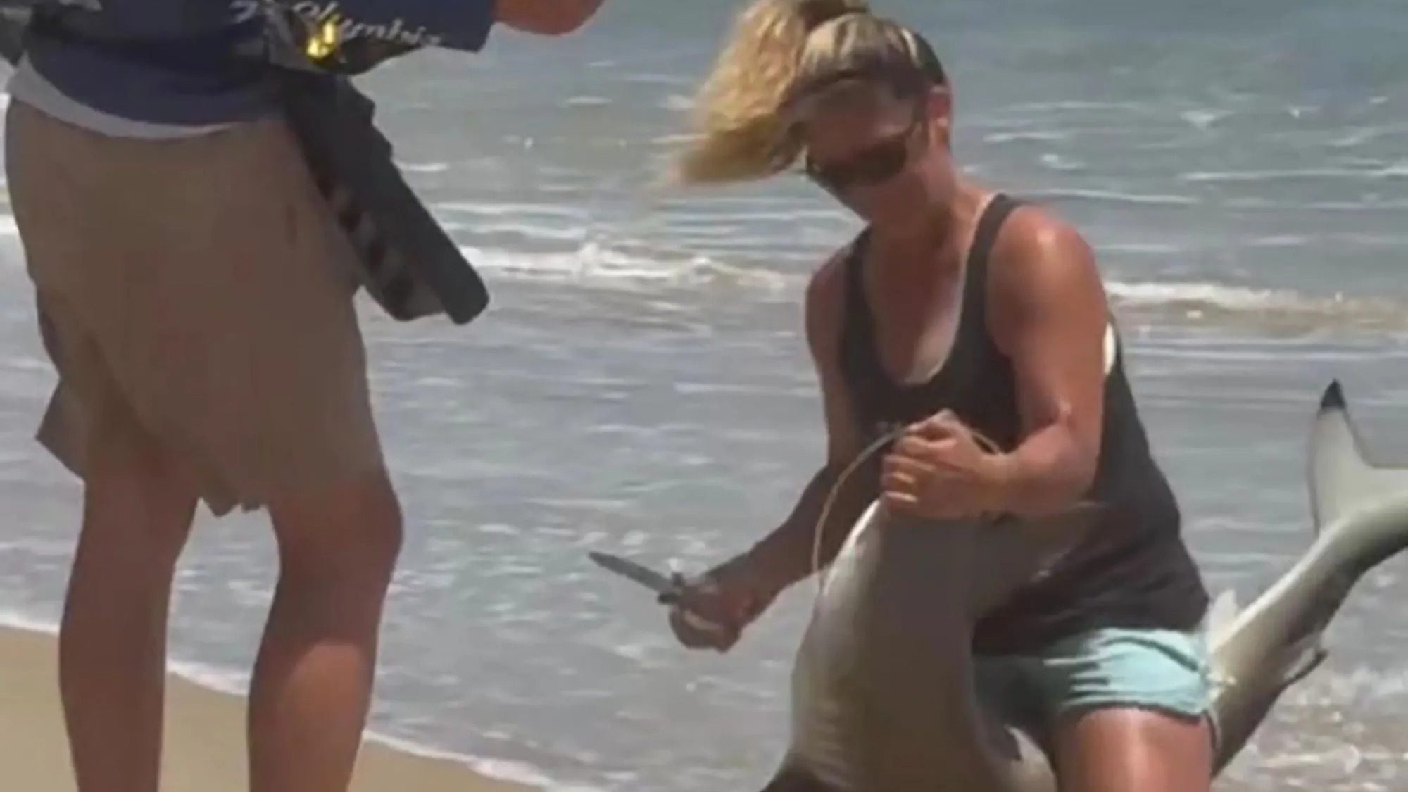 Shocking moment brave woman pins shark down then pulls hook out of its killer mouth during family beach trip