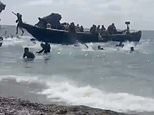 Sunbathers look on in shock as packed migrant boat arrives on Spanish beach and dozens of men run ashore and disappear